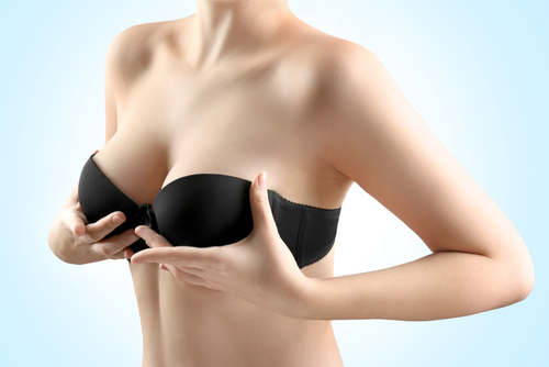 Upper torso of female model adjusting her bra