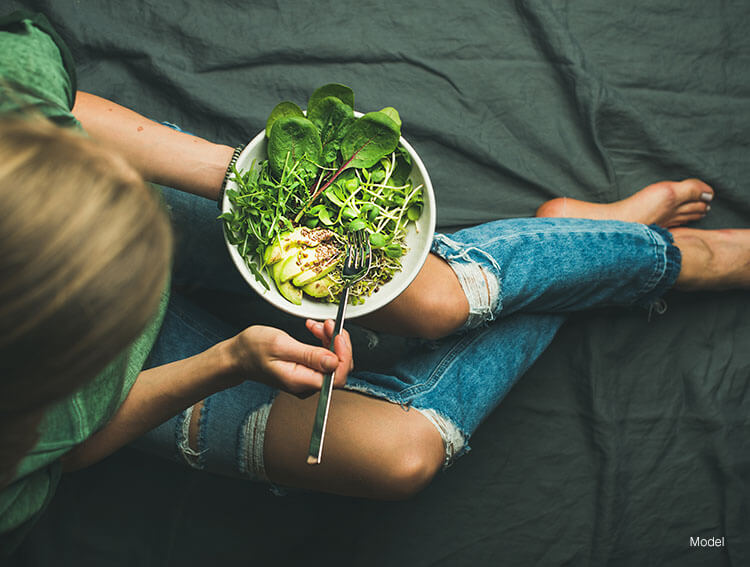 A woman eating a spinach salad t ensure optimal healing post liposuction surgery.