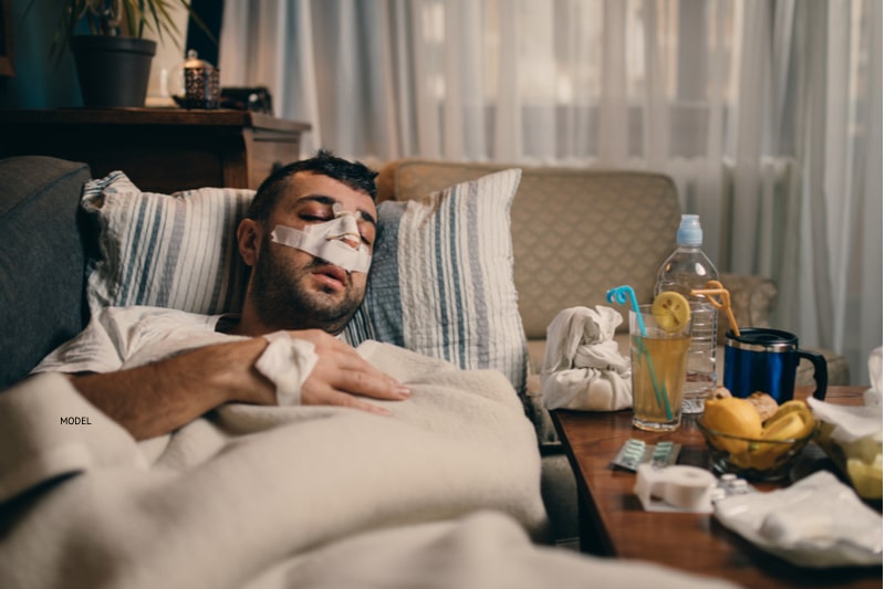 Many lying in bed with a bandaged nose while he recovers from nose surgery